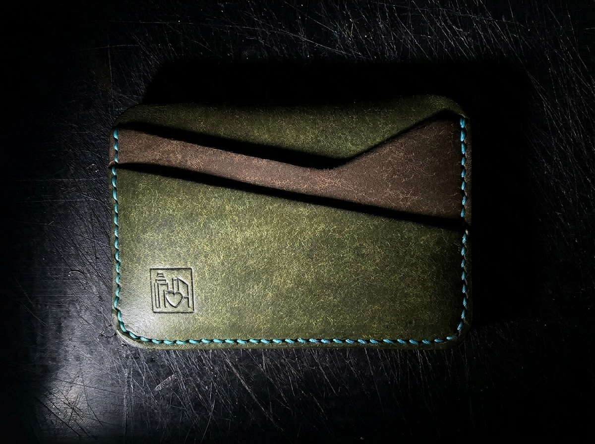 The Landscape Card Holder — olive green Pueblo leather exterior with turquoise hand stitching and Art by Steph Chan stamp